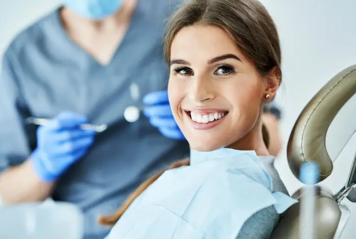 Woman in dental chair smiling with partial dentures in San Antonio